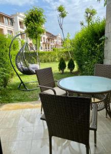 Un patio con mesa y sillas y un columpio. en Green life private garden studio, en Sozopol