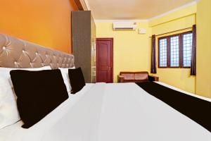 una camera da letto con un grande letto bianco e una sedia di Super Hotel O Vidhan Sabha Chowk Formerly Sunshine Guest House a Clement Town