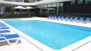 a swimming pool with lounge chairs and a building at Hotel Monte Lírio in Espinho