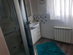 a bathroom with a sink and a shower with a blue rug at Дом in Odesa +15 photos