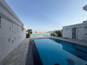 a swimming pool in front of a house at Soso beach villa in Durat Alarous
