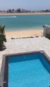 una piscina azul junto a una playa en Soso beach villa, en Durat Alarous