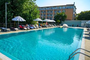 una grande piscina blu con sedie e ombrelloni di Hotel Queen Vera a Mamaia