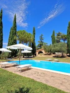 a swimming pool with two umbrellas and chairs and a pool at Borgo Melograno in Chiusi