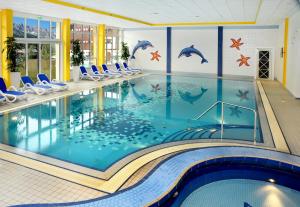 basen z delfinami pomalowanymi na ścianie w obiekcie All Inclusive - Marco Polo Alpina Familien- & Sporthotel w mieście Maria Alm am Steinernen Meer +37 zdjęć