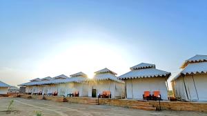 a row of white buildings with red chairs in front at Desert Glory Resort in Sām +25 photos