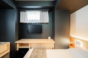 a bedroom with a bed and a desk and a tv at FL Hotel Asakusa in Tokyo
