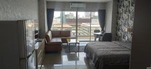a hotel room with a bed and a couch and a window at Pattaya Beach View Talay 6 by AEGEAN Suite Condo in Pattaya Central +35 photos