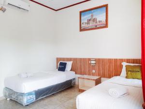 a room with two beds and a picture on the wall at Urbanview Hotel Sindu Syariah Bengkulu in Bengkulu