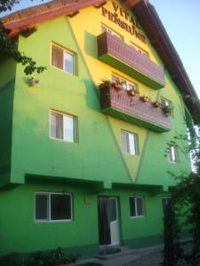 un edificio verde y amarillo con ventanas y balcones en Pensiunea Vital, en Chilia Veche