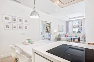 a white kitchen with a table and a living room at Solaga - Centro Alameda in Málaga