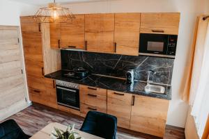 a kitchen with wooden cabinets and black counter tops at Chalet Mittner Wirt Grosskirchheim in Mitten