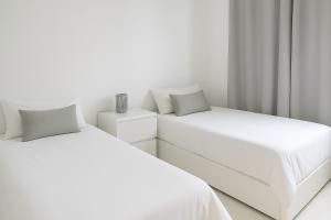 two beds in a room with white walls at Bianco d'Alghero - apartment by the sea in Alghero