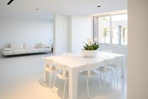 a white dining room with a white table and chairs at Bianco d'Alghero - apartment by the sea in Alghero