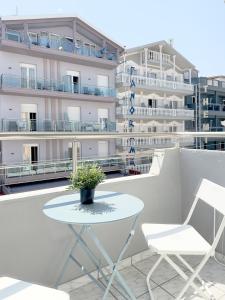 a white table and chairs on a balcony with buildings at Seagull apartments - Building A in Paralia Katerinis