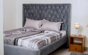 a bed with a gray headboard and a night stand at Hi-Pima Boutique Hotel in Kigali