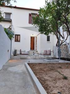 a white building with two benches and a tree at V House Cozy & Quiet Escape in Mytilini +21 photos