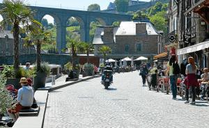 a street with people walking and a man riding a motorcycle at La Maison des Cordiers in Dinan