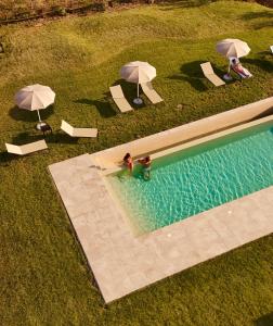 an overhead view of two people in a swimming pool with umbrellas at Radicata Tuscany Relais in Albinia