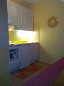 una pequeña cocina con armarios blancos y microondas en Mon Petit Canada, en Mittlach