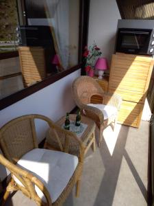 Un balcón con sillas de mimbre y una mesa con botellas encima. en Mon Petit Canada, en Mittlach
