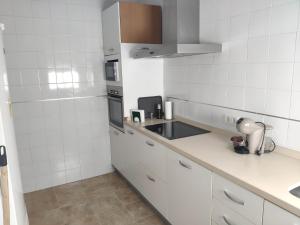 cocina con paredes de azulejos blancos y armarios blancos en Casa turística AZAHAR, en Villablanca