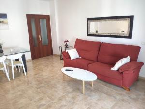 Una sala de estar con un sofá rojo y una mesa. en Casa turística AZAHAR, en Villablanca