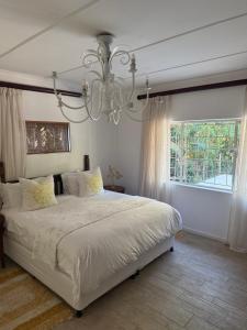 a bedroom with a large white bed and a chandelier at Beachfront petfriendly cottage in Zinkwazi Beach