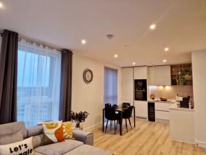 a living room with a couch and a table and a kitchen at Wembley Cozy Cloud Waterfront Retreat with Parking near Wembley stadium in London