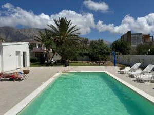 a swimming pool with chairs and a palm tree at Villa Priscilla in Cinisi