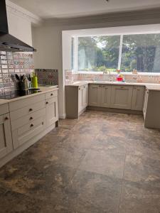 a large kitchen with white cabinets and a large window at Lower Milntown Farm in Ramsey