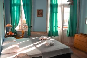 a bedroom with green curtains and a bed with towels at Old Port Manor in Mirina