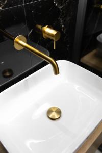 a white sink with a gold faucet on it at Calma Luxury Suites in Paralia Dionysiou +52 photos
