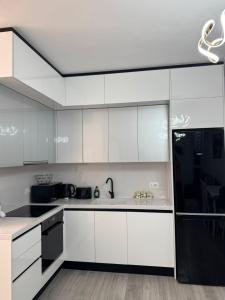 a kitchen with white cabinets and a black refrigerator at Bratti's Apartment 2 Near Tirana Center And Mother Teresa International Airport in Laknas