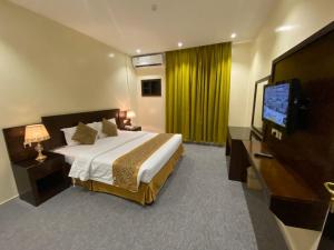 a hotel room with a bed and a flat screen tv at راحة للأجنحة الفندقية Raha hotel suites in Hail