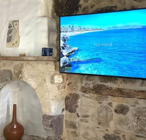 a flat screen tv hanging on a stone wall at Casas di Pietra in Paradeísi