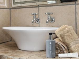 a bathroom sink with a bottle of soap and towels at Cozy Corner in Bloemfontein +48 photos