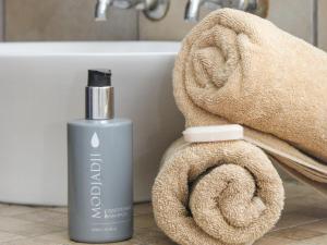 a bottle of soap and a towel next to a bath tub at Cozy Corner in Bloemfontein