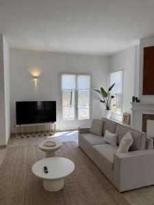 a white living room with a couch and a tv at Panorama by maison bacou in Carcassonne