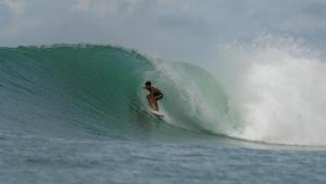 a man riding a wave on a surfboard in the ocean at Nias Surf Stay in Lagudri
