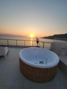 una vasca da bagno su un balcone con il tramonto di Stylish Rooftop Retreat with Hot Tub with Loutraki Beach a Loutraki