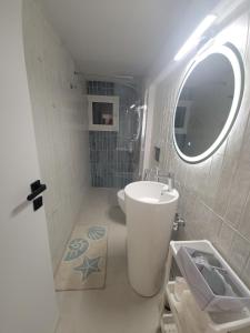 un bagno con lavandino, WC e specchio di Stylish Rooftop Retreat with Hot Tub with Loutraki Beach a Loutraki