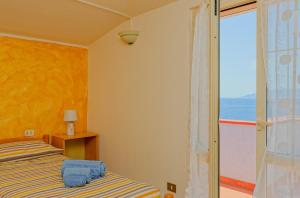 een slaapkamer met een bed en uitzicht op de oceaan bij Mermaid in Cala Gonone