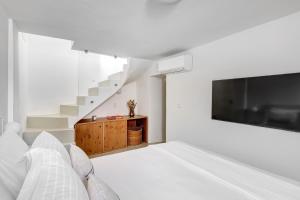a bedroom with a bed and a tv and stairs at Aplotis home in Ermoupoli