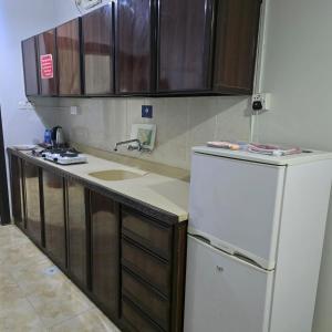 a kitchen with a white refrigerator and wooden cabinets at شركة فؤاد علي العزي للشقق المخدومة in Taif +11 photos
