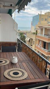 einen Holztisch auf einem Balkon mit Meerblick in der Unterkunft Alojamiento con vistas al mar en Puerto Sagunto in Puerto de Sagunto