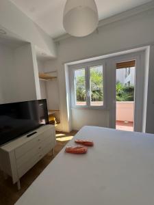 Un dormitorio con una cama blanca y un televisor de pantalla plana. en Tiber Domus Fiumicino - Apt 2, en Fiumicino