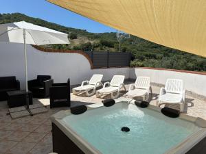 Antica Sorgente villa في أغروبولي: حوض استحمام ساخن مع كراسي ومظلة على الفناء