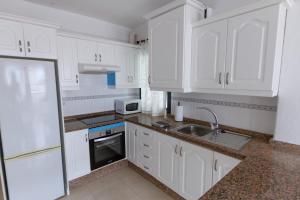 a white kitchen with white cabinets and a sink at Rayo de Sol Los Cristianos in Arona +2 photos