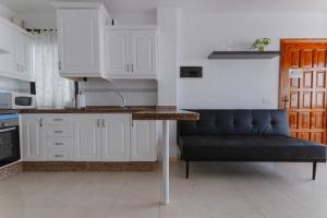 a kitchen with white cabinets and a black bench at Rayo de Sol Los Cristianos in Arona